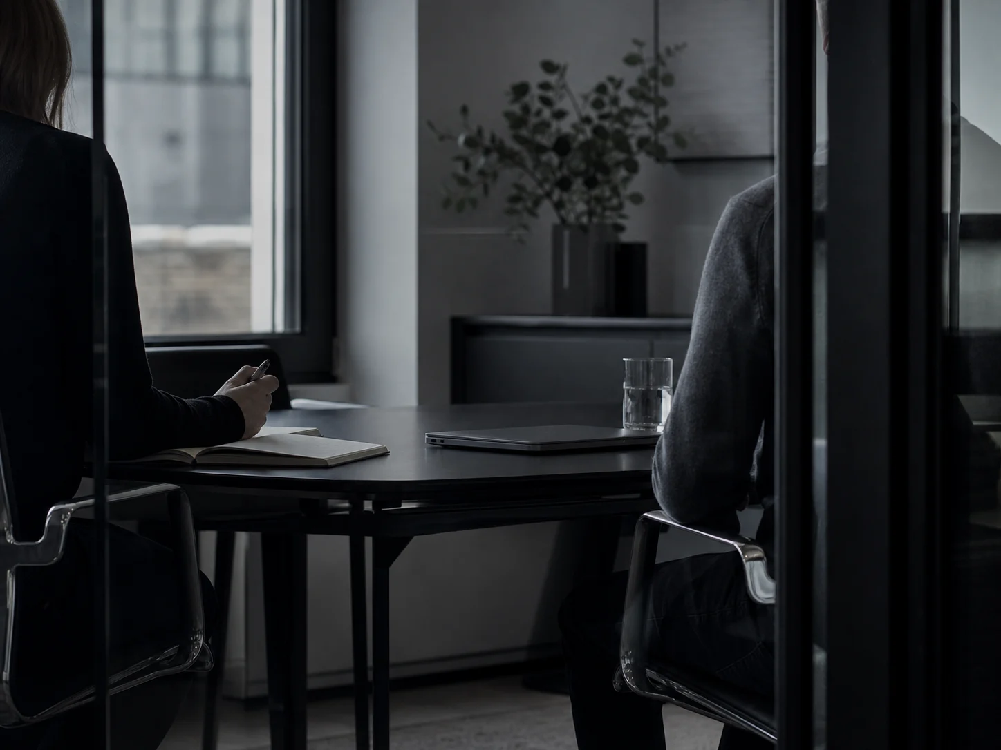 En rekryterare och en kandidat sitter i ett avskalat mötesrum.